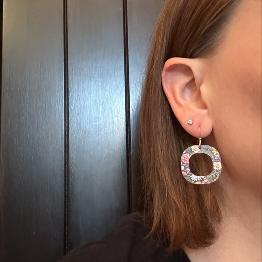Model wearing lightweight floral acrylic earrings with an open circle shape and gold-tone stainless steel hooks.
