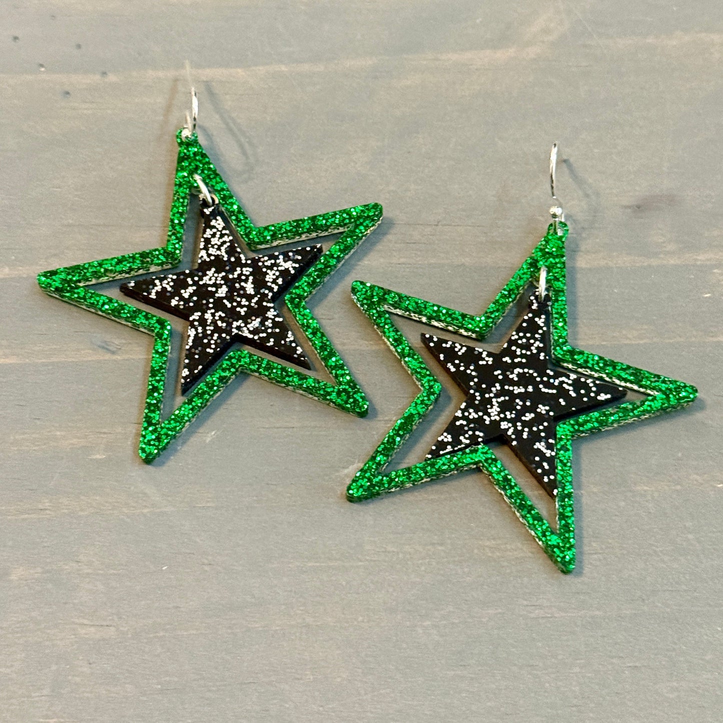 Green and black glitter stars earrings on silver hooks, lightweight acrylic dangles for game day, handmade in Texas by half turn designs
