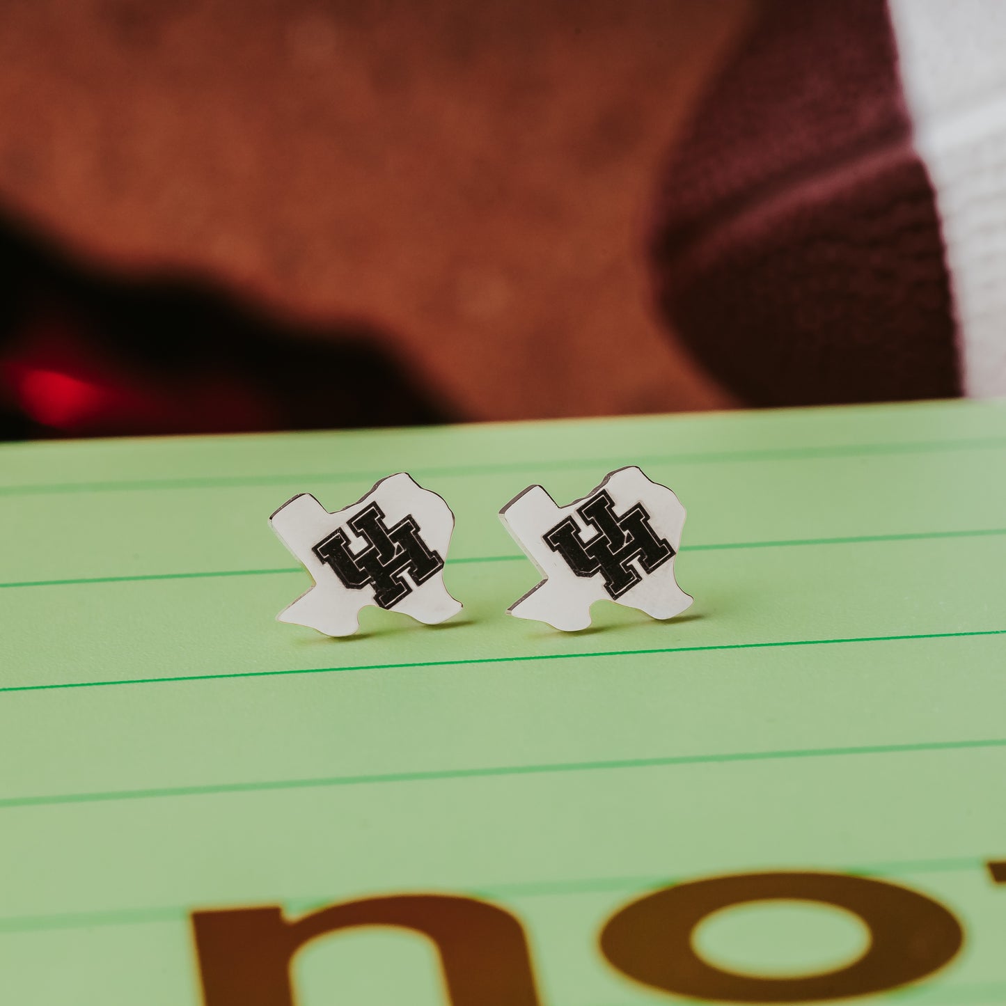 University of Houston Texas-Shaped Studs. These earrings are made from stainless steel, available in gold or silver finish and engraved with the UH Cougars logo. They are officially licensed earrings made by Half Turn Designs. Shown here in silver finish.