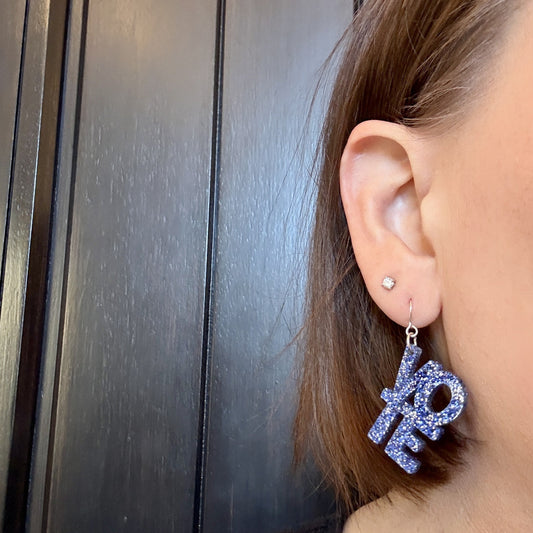 Model wearing Blue glitter vote earrings with stacked VOTE letters and silver ear wires