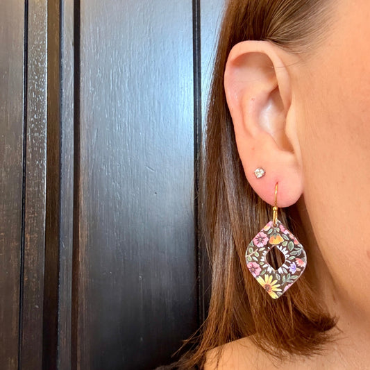 Model wearing clear acrylic floral dangle earrings with stainless steel gold-tone earring hooks