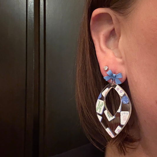 Model wearing Mahjong acrylic earrings in blue chinoiserie design topped with blue bows with a stainless steel pin