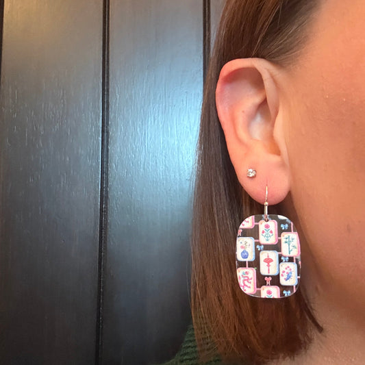 Model wearing Lightweight mahjong tile dangle earrings in a rounded rectangle shape with multicolor tile artwork on clear acrylic