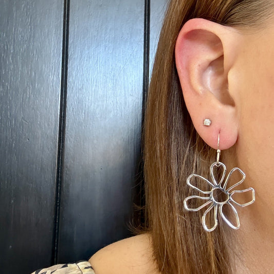 Model wearing Silver daisy floral earrings with lightweight open petal design by Half Turn Designs