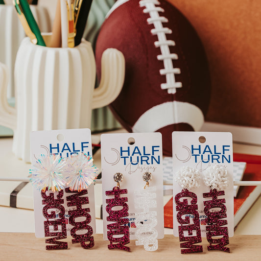 Texas A&M Officially Licensed Mix and Match Dangle Earrings in maroon and white glitter. Create your own pair of earrings combining TAMU phrases like "Aggies", "Gig 'em", "Whoop" and "Howdy" into a pair of earrings with your choice of glitter color and earring topper.