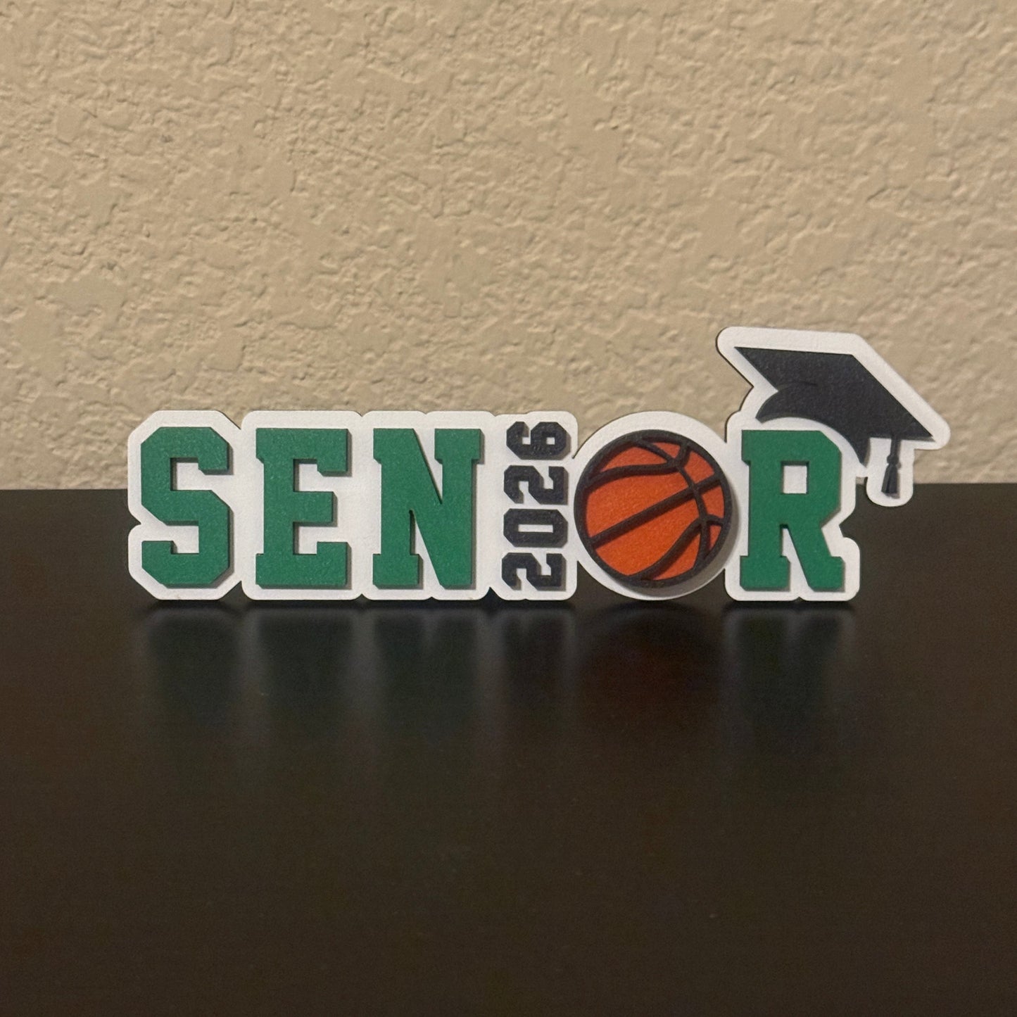 Class of 2026 senior basketball sign with basketball graphic and graduation cap, with green accents.  Graduation party and high school basketball banquet decor