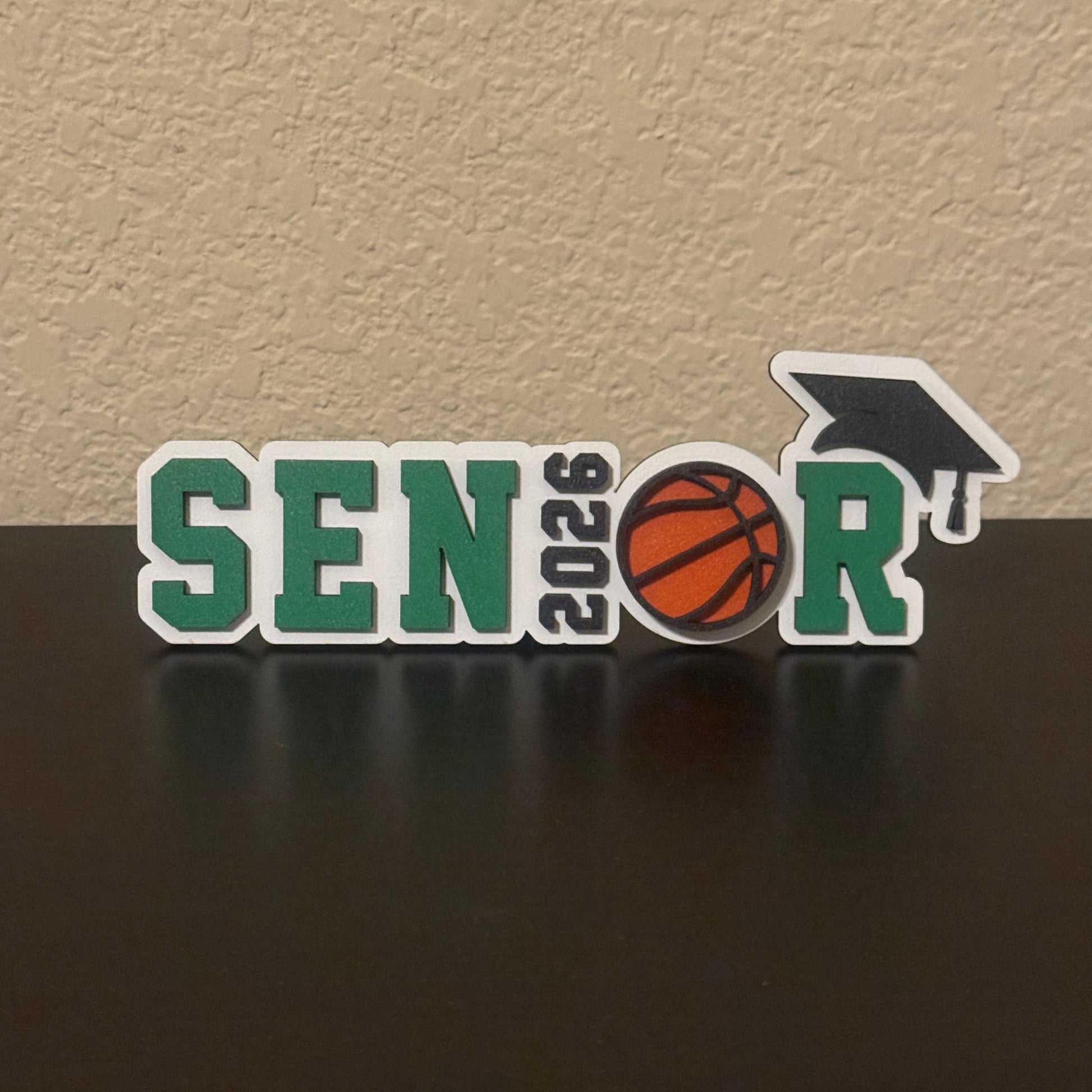 Class of 2026 senior basketball sign with basketball graphic and graduation cap, with green accents.  Graduation party and high school basketball banquet decor