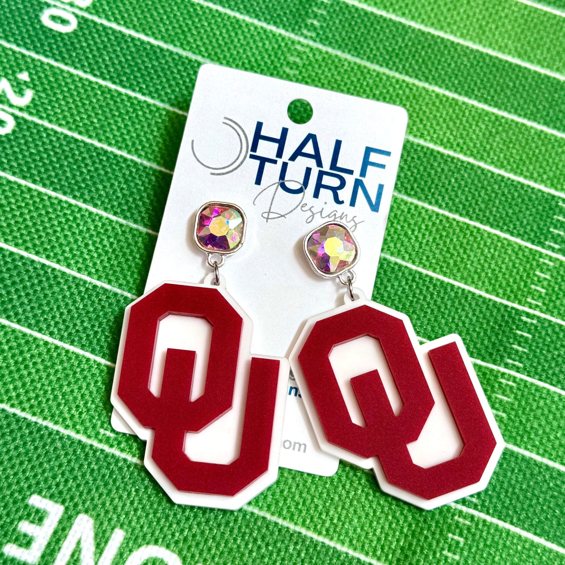 Officially licensed University of Oklahoma game day earring collection by Half Turn Designs. These earrings are available in combinations of crimson and white acrylic, including glitter. Available in a eight different fun toppers for OU game days and as a gift for your favorite Oklahoma Sooner. Crimson on White with AB Iridescent Topper with Silver hardware shown here.
