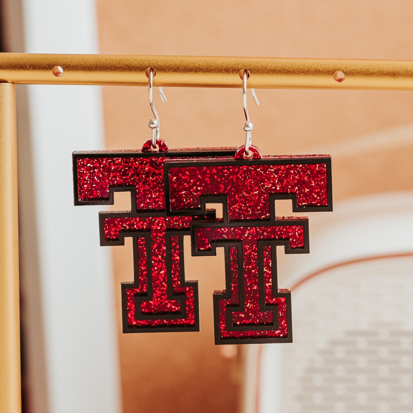 Officially licensed Texas Tech Double T acrylic earrings shown in red glitter with black layered accents.