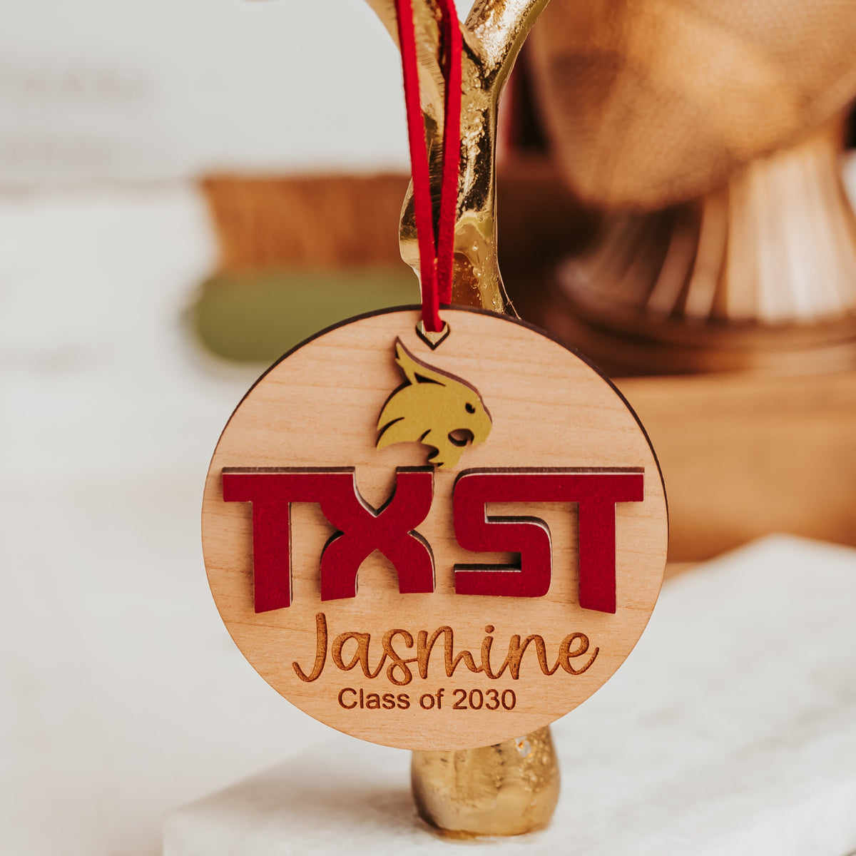 Cherry wood Texas State ornament with gold Bobcat, maroon TXST letters and engraved name and class year on a maroon cord