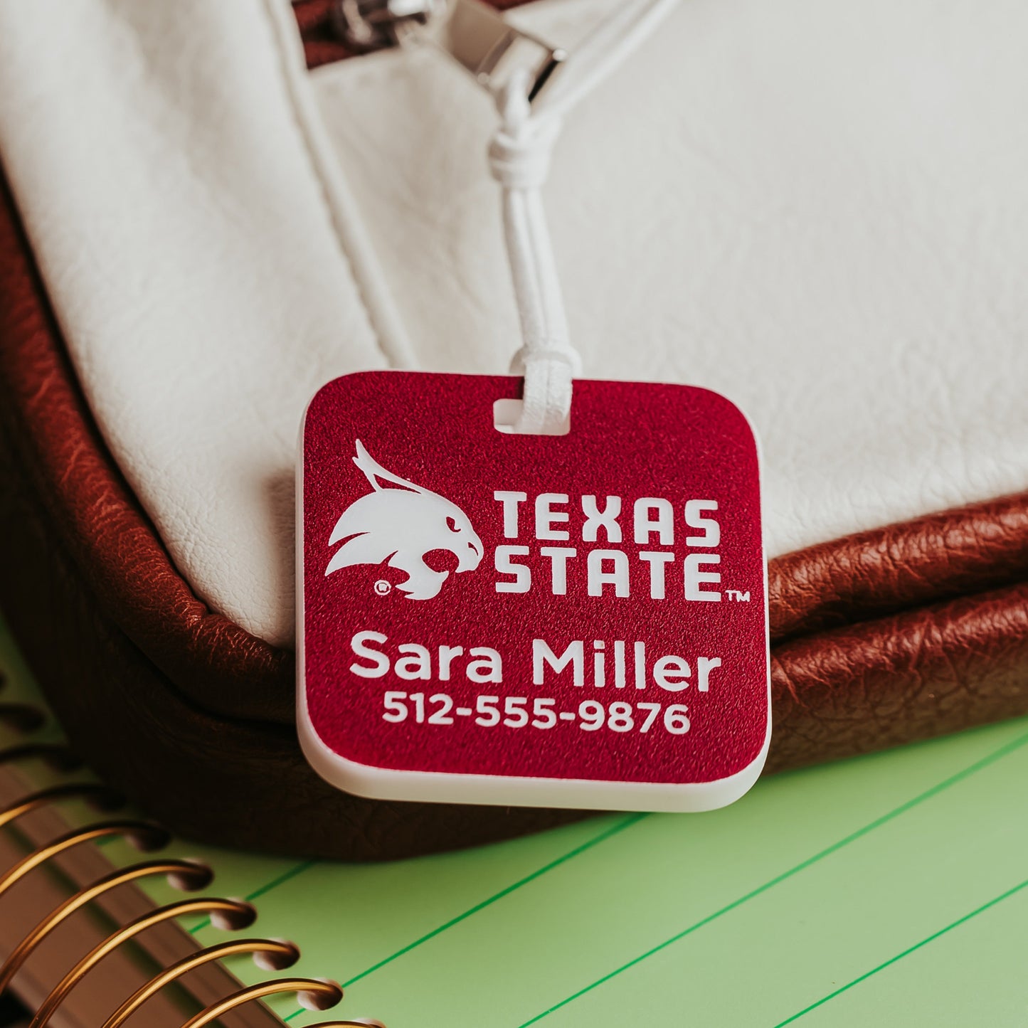 Personalized Texas State luggage tag in crimson acrylic that engraves white, engraved with the Bobcat logo, TEXAS STATE wordmark, a name, and phone number