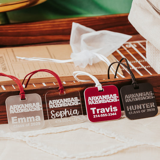 University of Arkansas Razorbacks acrylic luggage tags. These luggage tags are 2" squares, available in 1/8" or 1/4" clear, frosted, black or crimson acrylic, each engraved with a name and contact information.