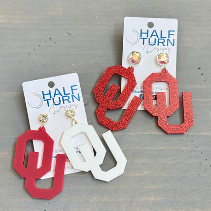 University of Oklahoma OU Game Day Dangle acrylic earrings. Officially Licensed Oklahoma Sooners jewelry by Half Turn Designs.
From left to right - 
- Crimson and white acrylic with rhinestone earring topper- White acrylic with crimson beaded toppers
- Crimson glitter acrylic with AB iridescent square jewel topper