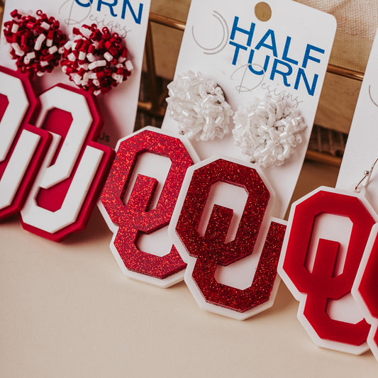 Officially licensed University of Oklahoma game day earring collection by Half Turn Designs. These earrings are available in combinations of crimson and white acrylic, including glitter. Available in a eight different fun toppers for OU game days and as a gift for your favorite Oklahoma Sooner.