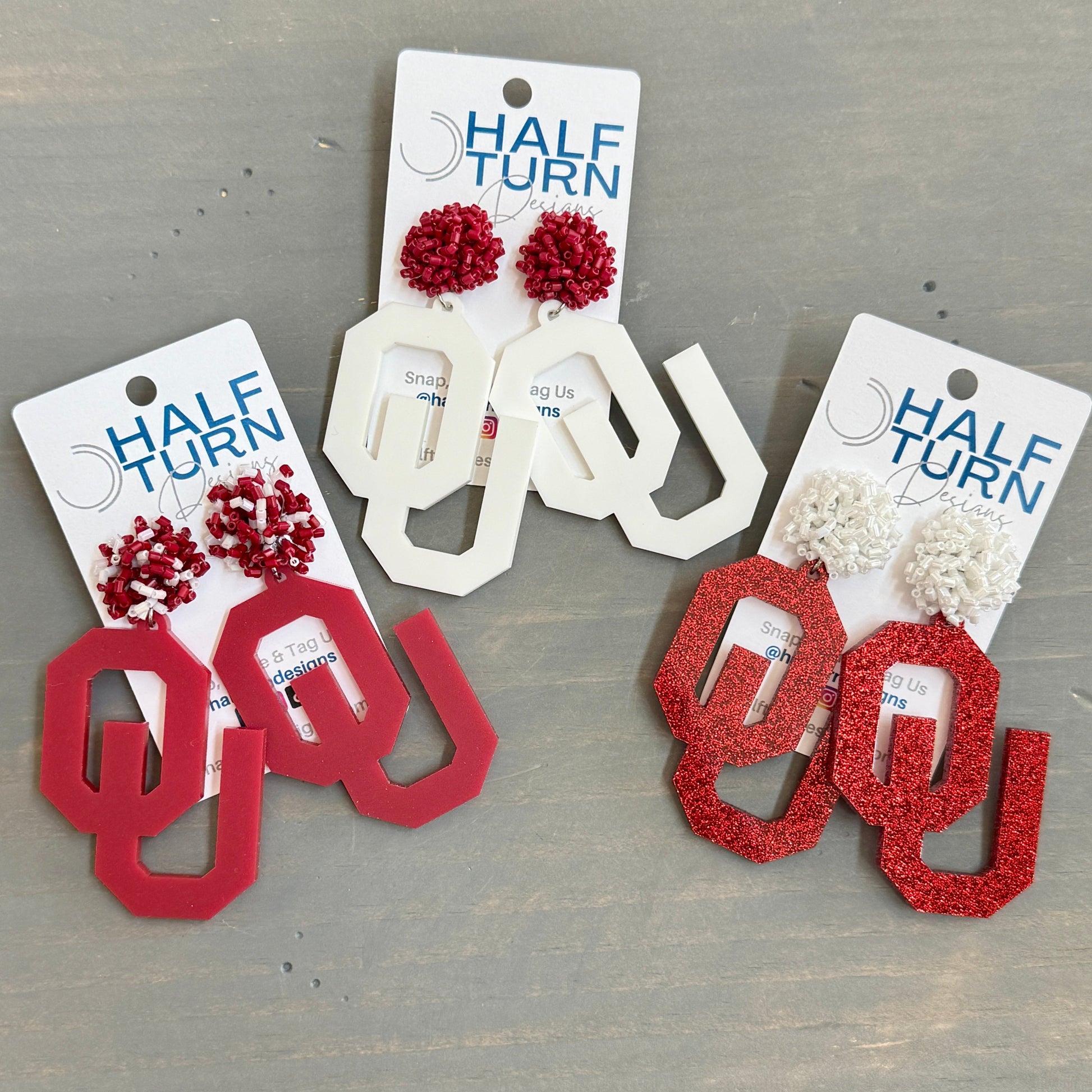 University of Oklahoma OU Game Day Dangle acrylic earrings. Officially Licensed Oklahoma Sooners jewelry by Half Turn Designs.
From left to right - 
- Crimson acrylic with crimson and white beaded toppers
- White acrylic with crimson beaded toppers
- Crimson glitter acrylic with white beaded toppers