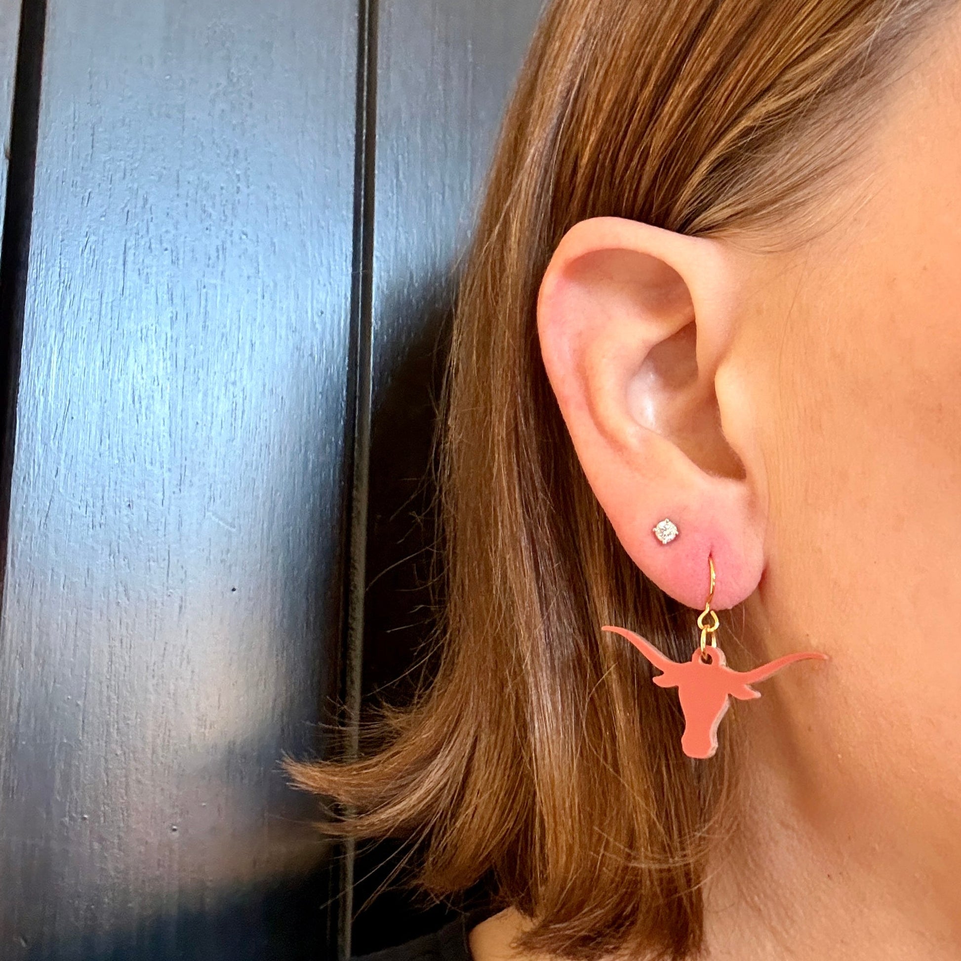 Model wearing burnt orange acrylic longhorn game day dangle earrings