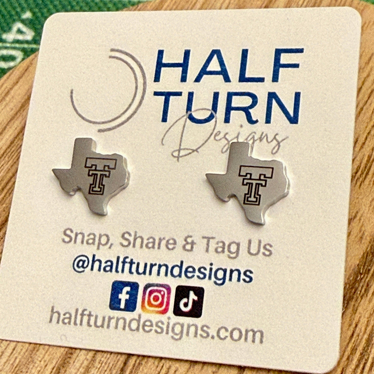 Close-up of silver-tone Texas-shaped Texas Tech stud earrings showing the engraved Double T detail
