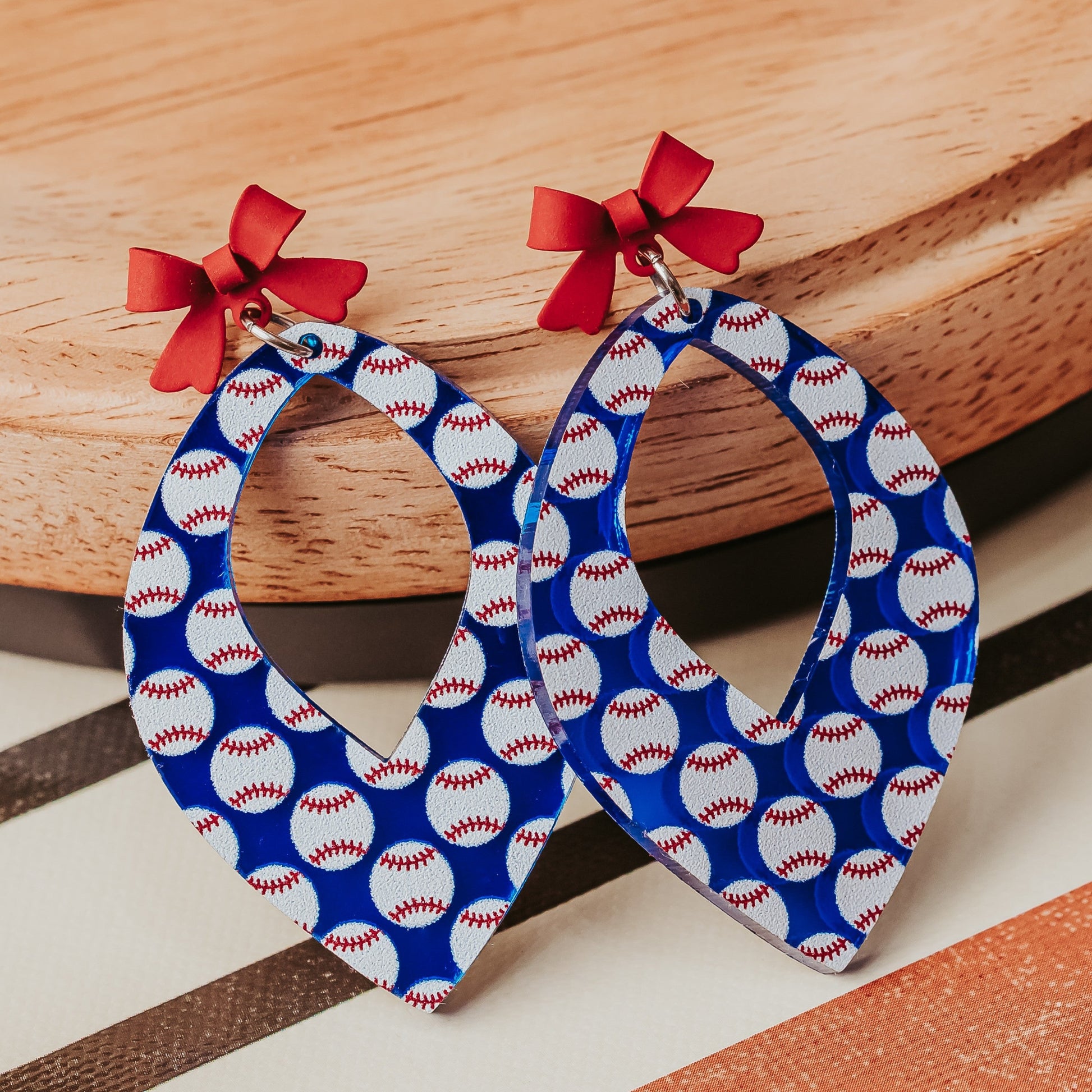Close up of Blue mirror acrylic Baseball mom gift earrings with red bow accent