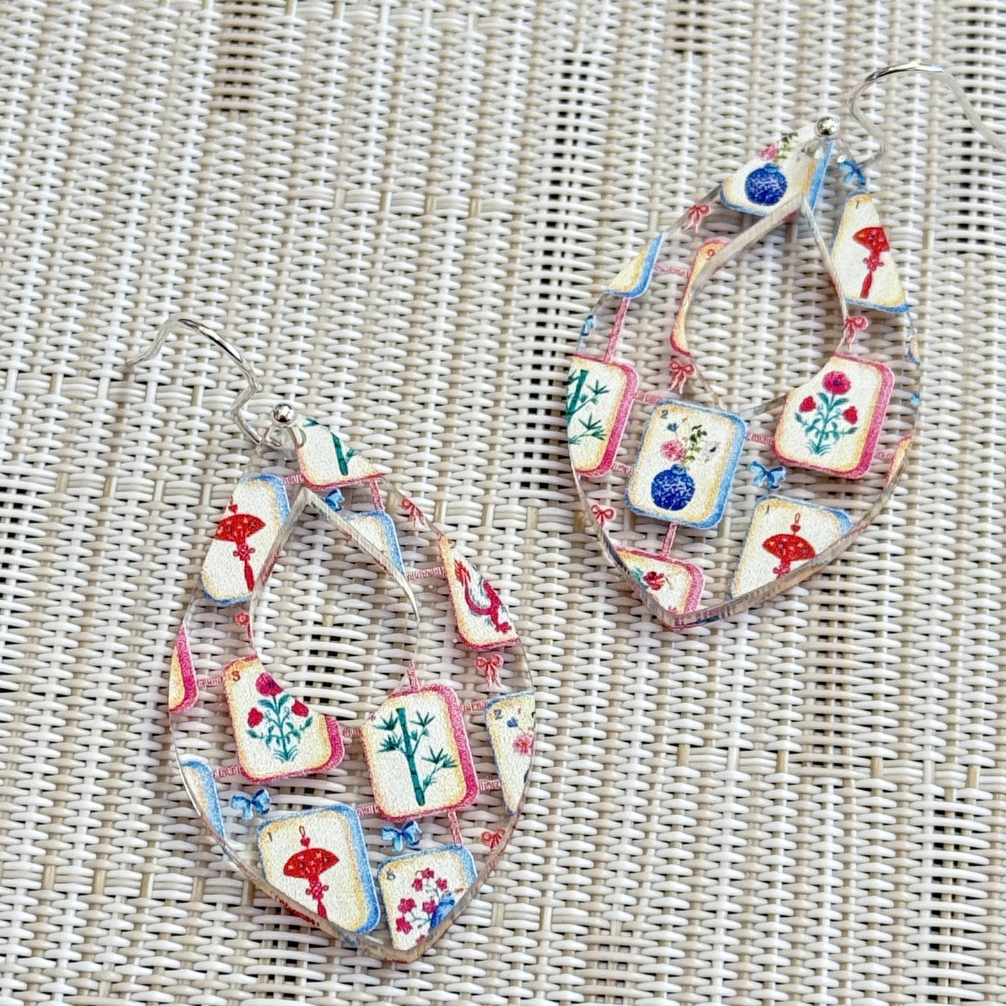 Close-up of colorful mahjong earrings with a tile pattern printed on clear acrylic  in a teardrop shape