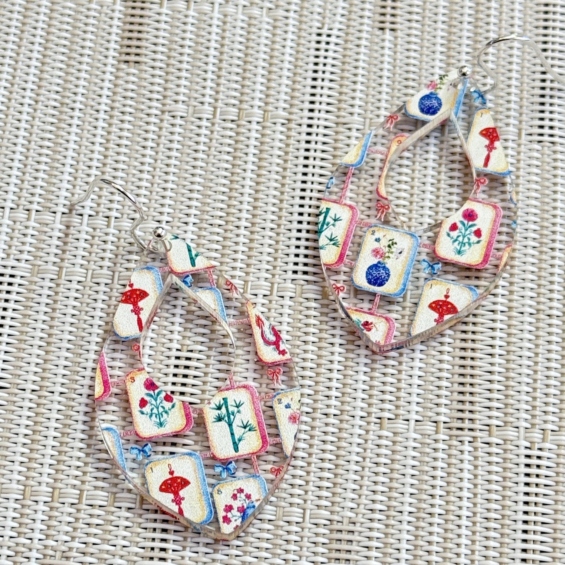 Close-up of colorful mahjong earrings with a tile pattern printed on clear acrylic  in a teardrop shape