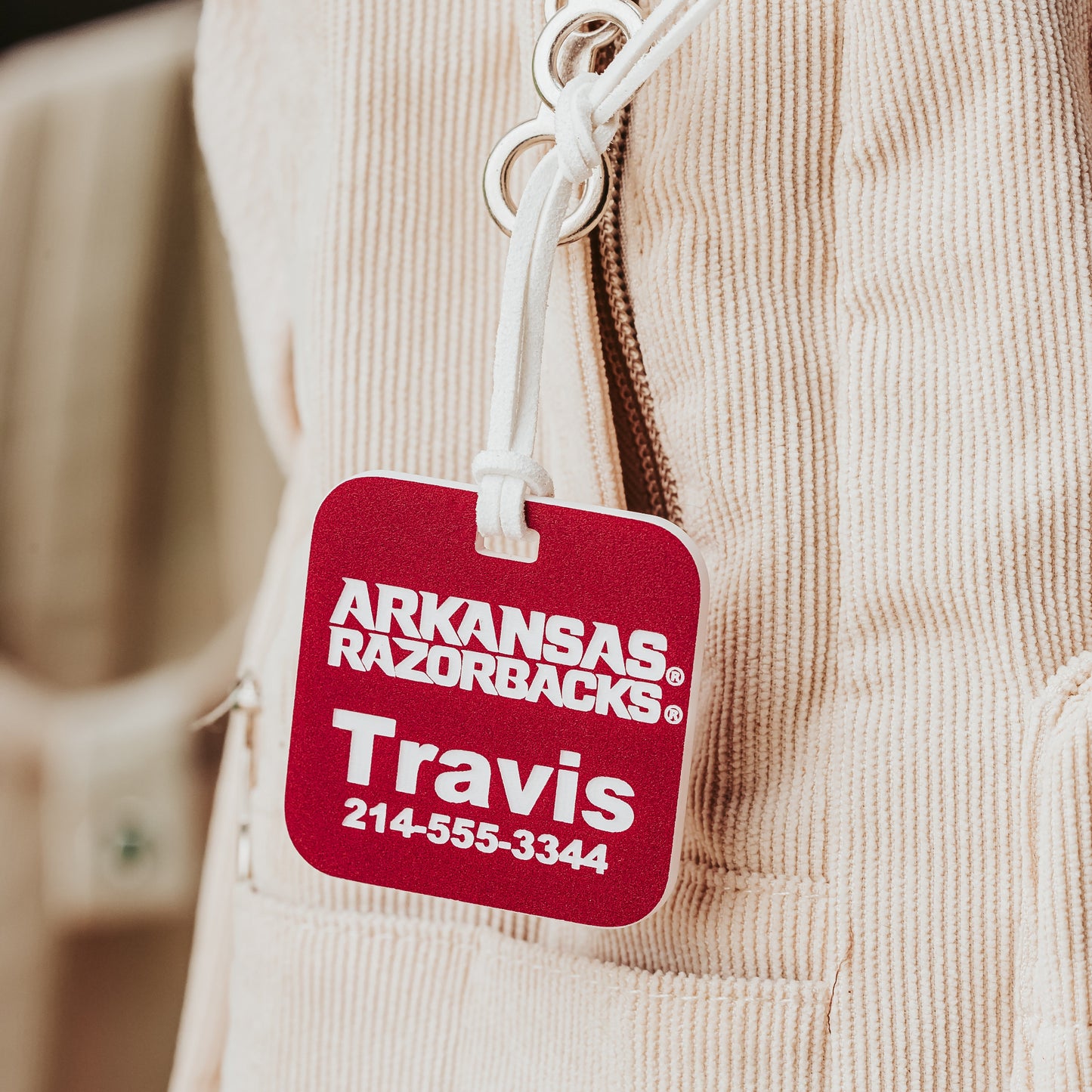 Close-up of University of Arkansas Razorbacks square luggage tags. Shown here in crimson acrylic that engraves white. Personalized with your information to identify your luggage faster.