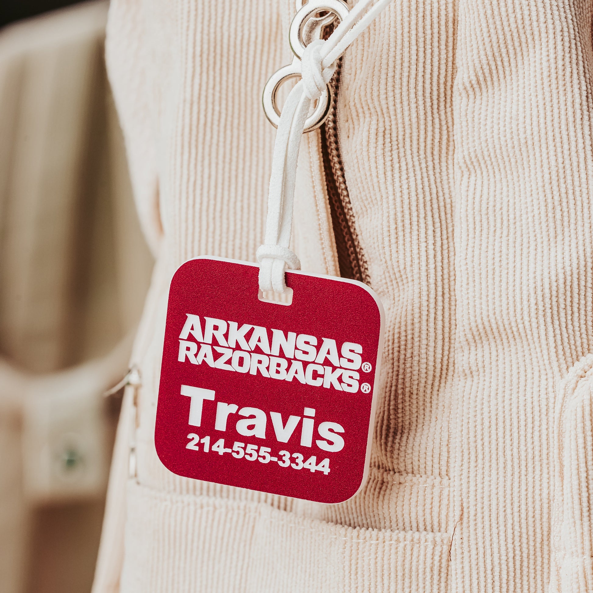 Close-up of University of Arkansas Razorbacks square luggage tags. Shown here in crimson acrylic that engraves white. Personalized with your information to identify your luggage faster.