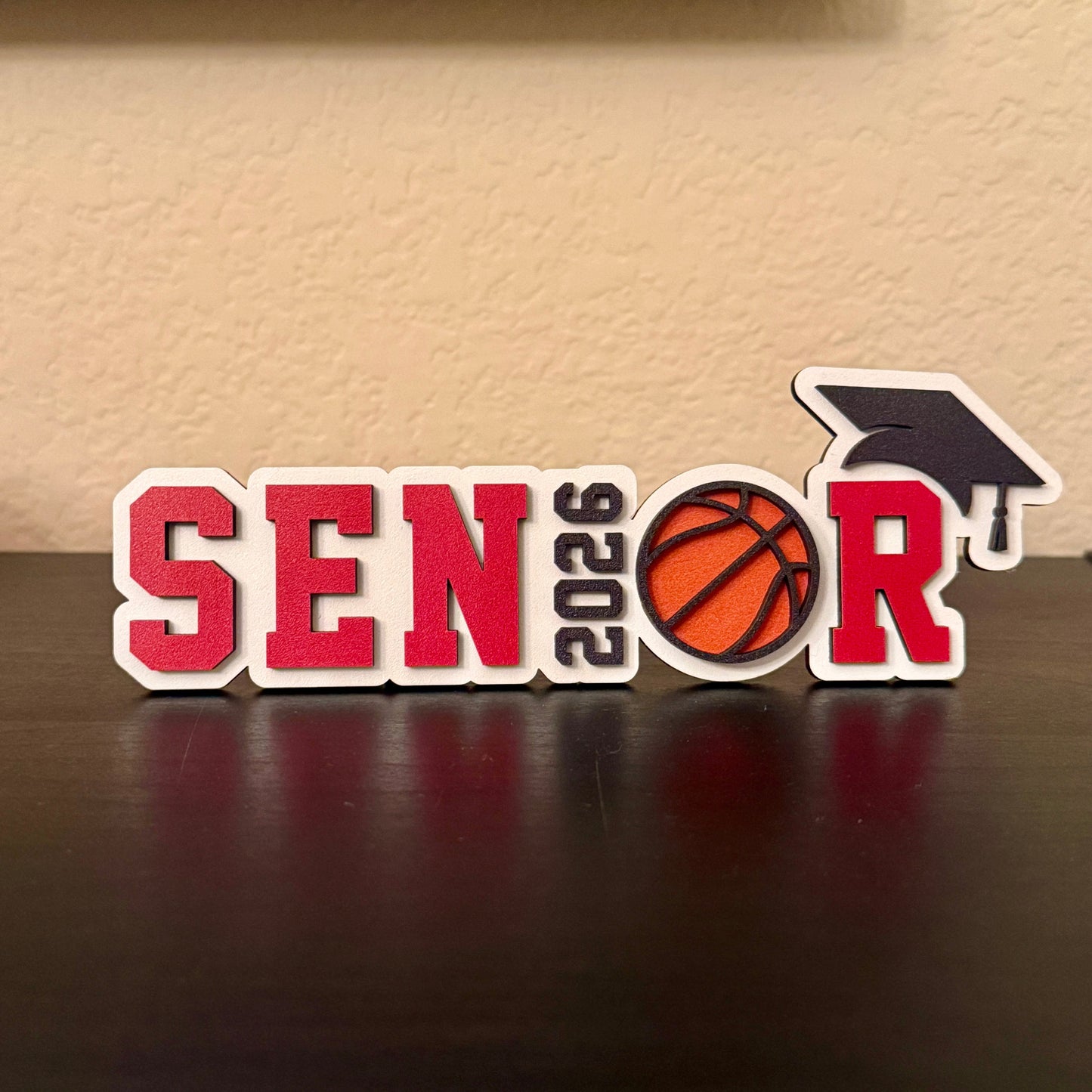 Class of 2026 senior basketball sign with basketball graphic and graduation cap. Shown here in red.  Graduation party and high school basketball banquet decor