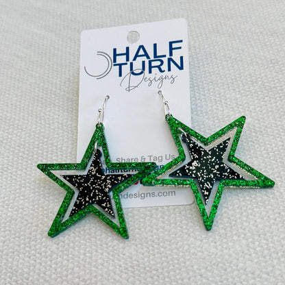 Green and black glitter stars earrings on silver hooks, lightweight acrylic dangles for game day, handmade in Texas by half turn designs.