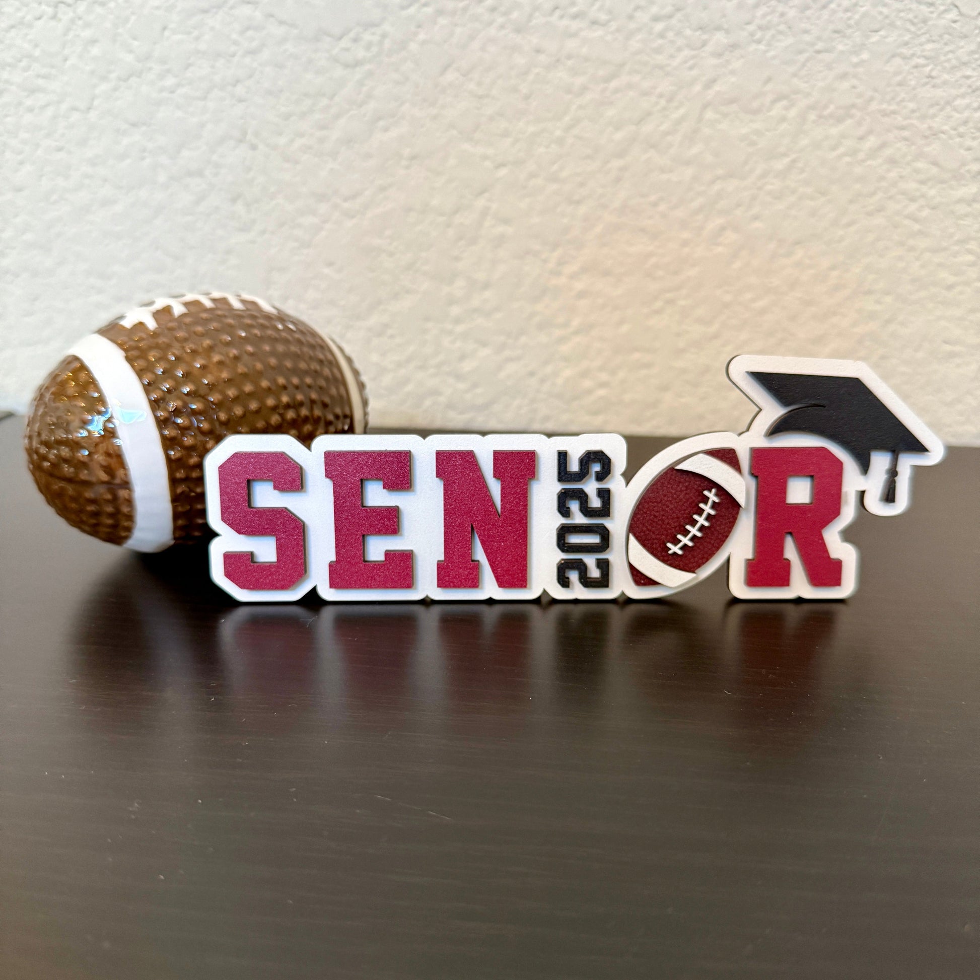 Football Graduation sign for High School Seniors. White Wood base with football and graduation accents; spells senior.