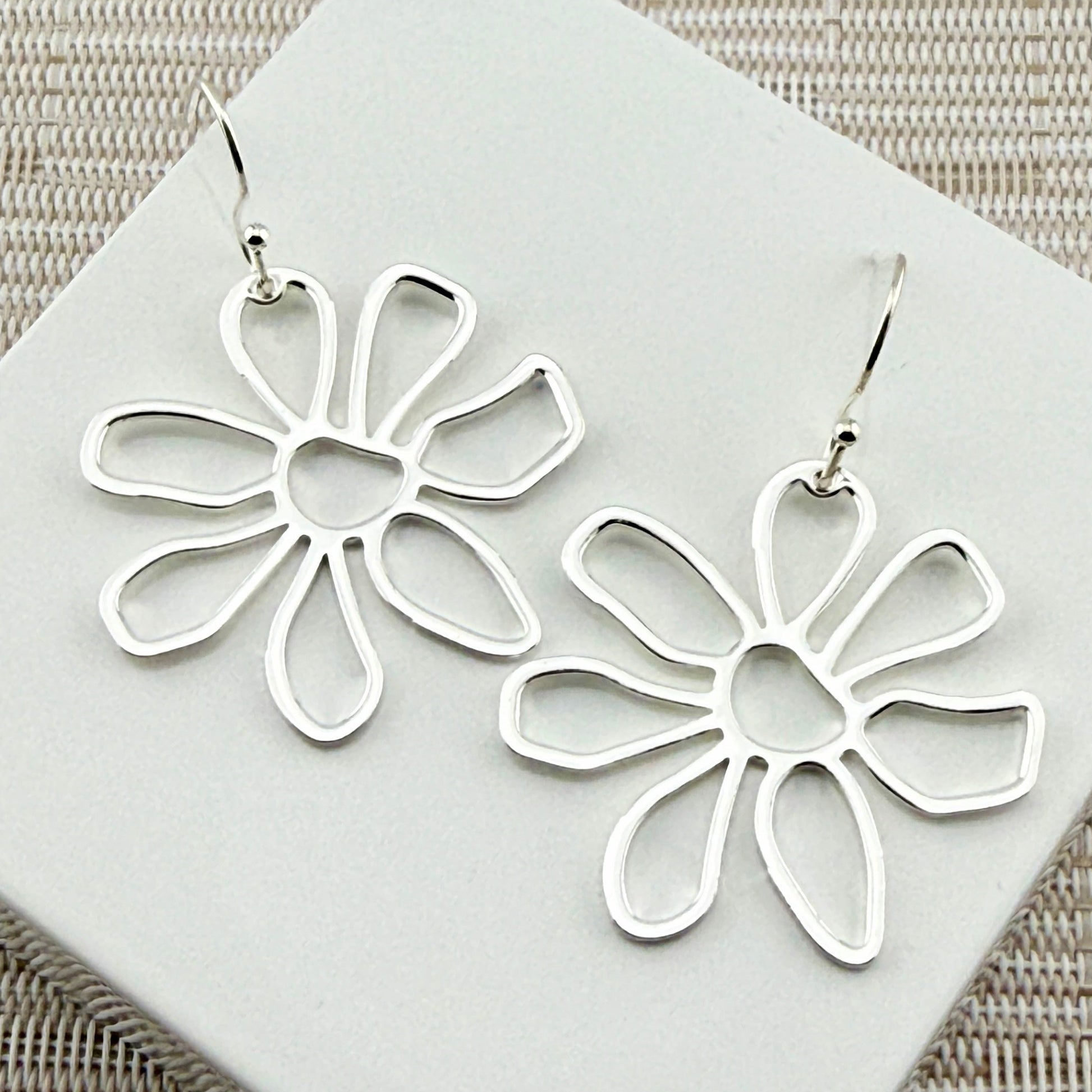 Lightweight daisy botanical silver earrings displayed on white box