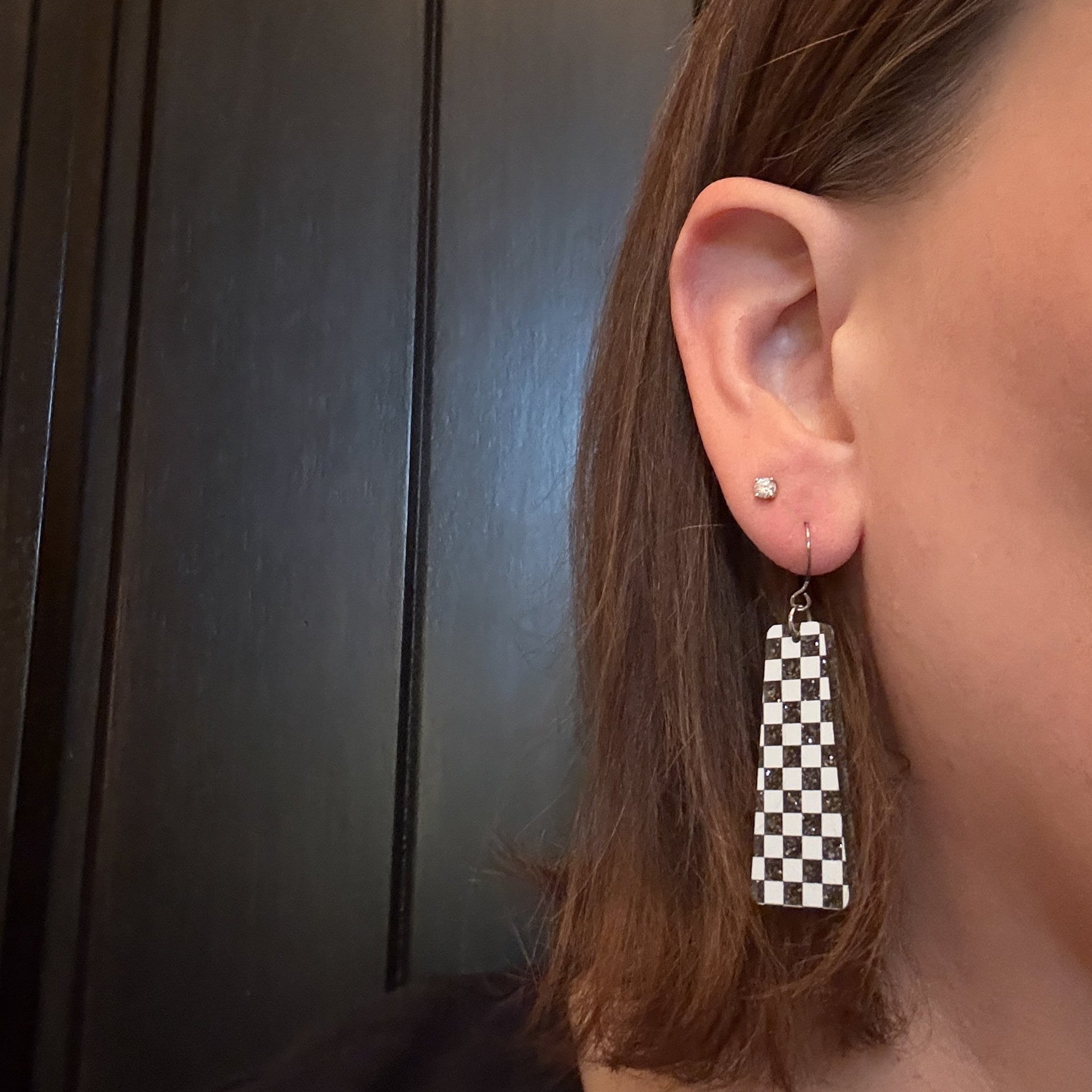 Model wearing Black and White Checkered Dangle Earrings with silver-toned earring hooks