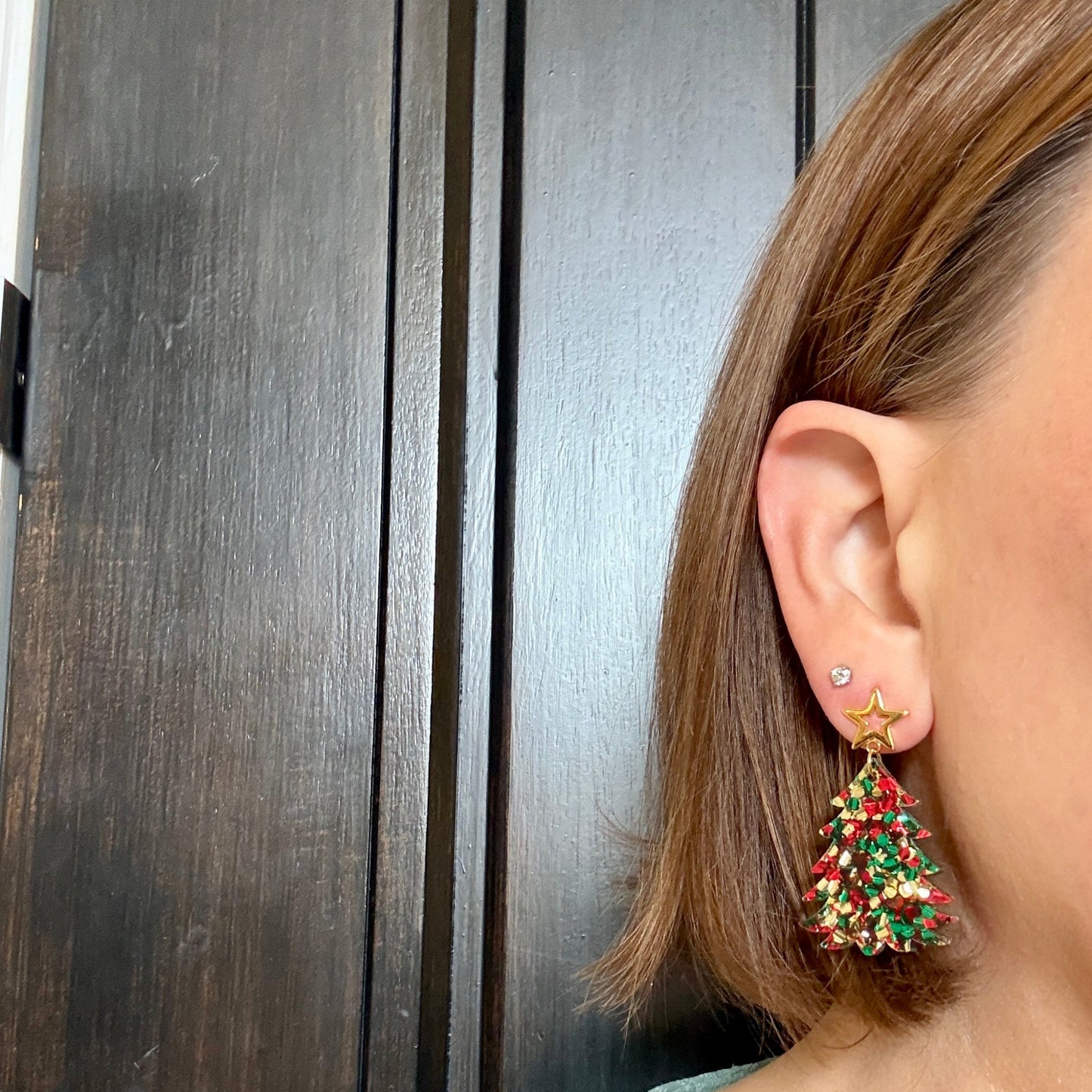 Model wearing Christmas tree earrings in red, green and gold chunky glitter acrylic with gold-tone star studs.