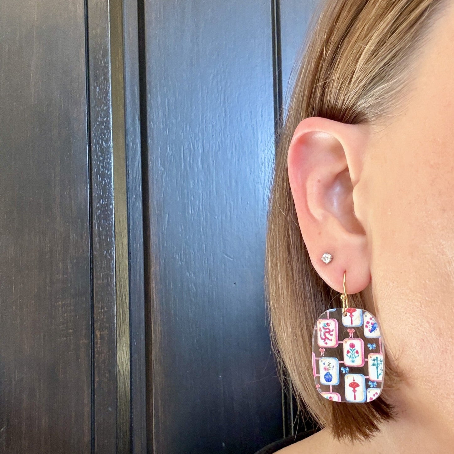 Model wearing Lightweight mahjong tile dangle earrings in a rounded rectangle shape with multicolor tile artwork on clear acrylic