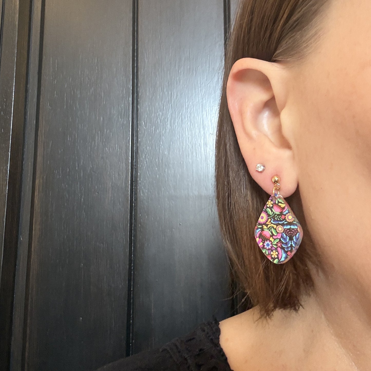 Model wearing Mexican floral diamond-shaped acrylic earrings with gold stainless steel studs
