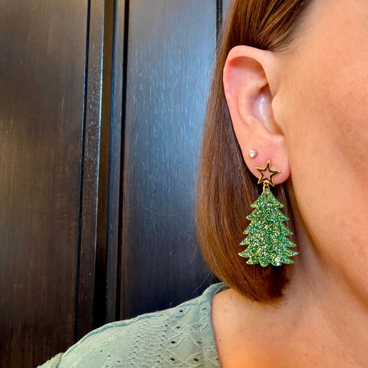 Model wearing Green and gold glitter Christmas tree earrings with gold star studs