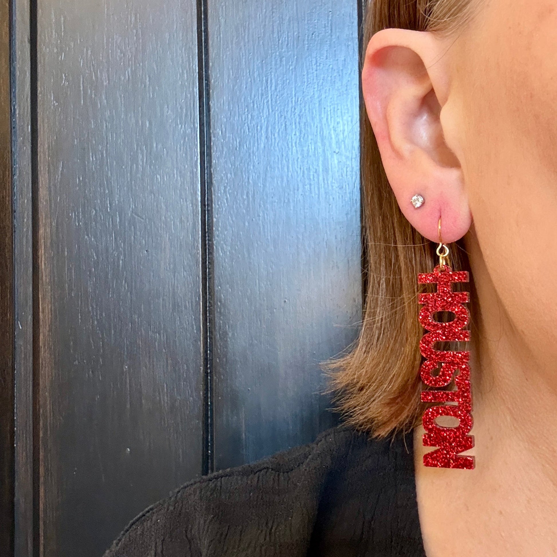 Model wearing university of houston dangle earrings in red glitter.