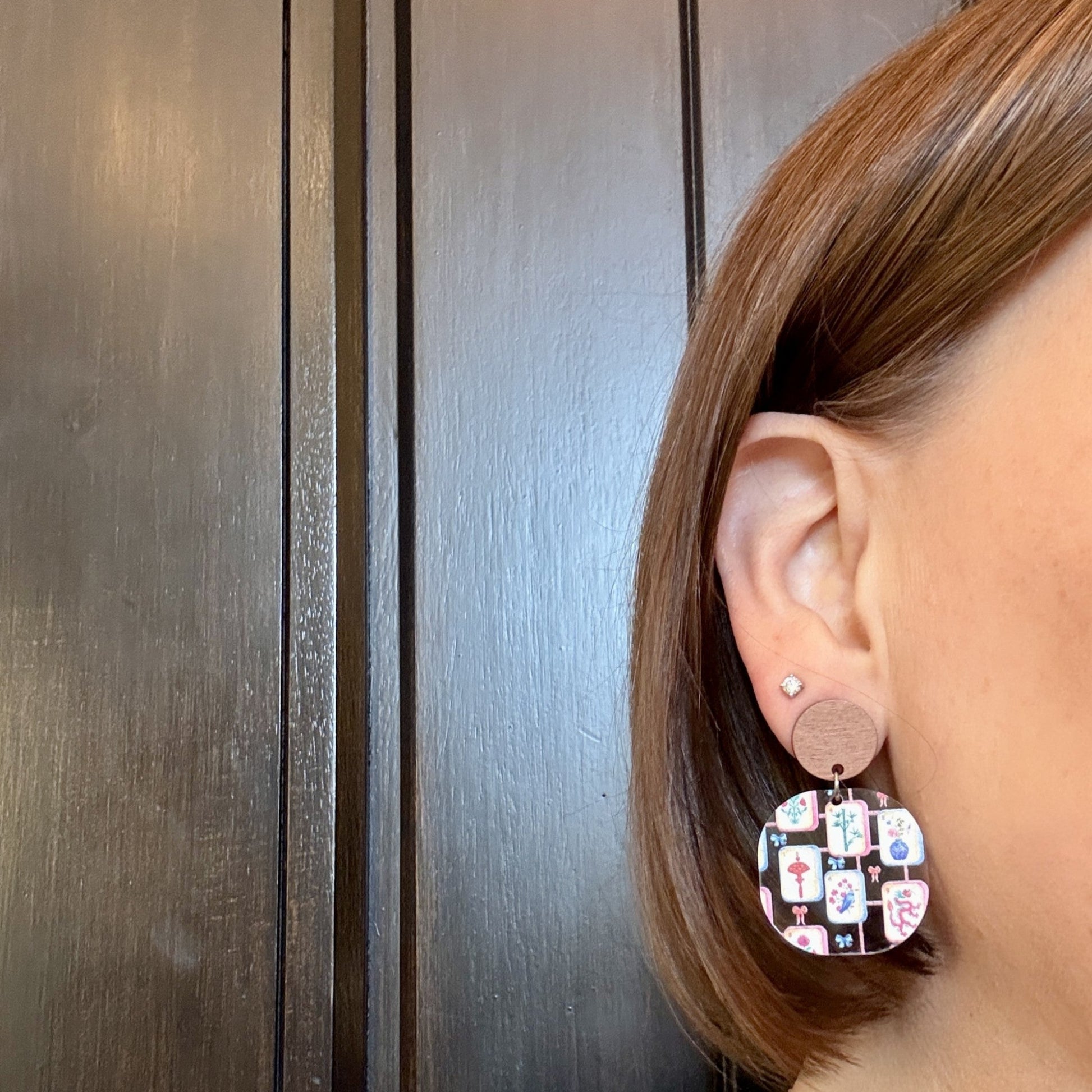 Model wearing mahjong acrylic earrings in rounded square shape with walnut wood studs