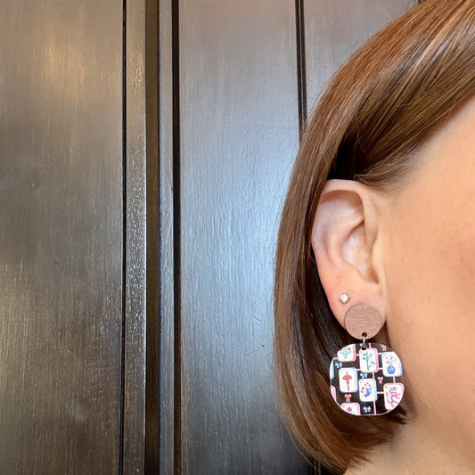 Model wearing mahjong acrylic earrings in rounded square shape with walnut wood studs