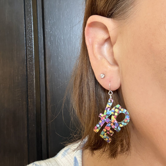 Model wearing VOTE earrings with colorful rainbow design, lightweight statement election day jewelry to show your support for gay and lesbian rights, civic pride rainbow earrings