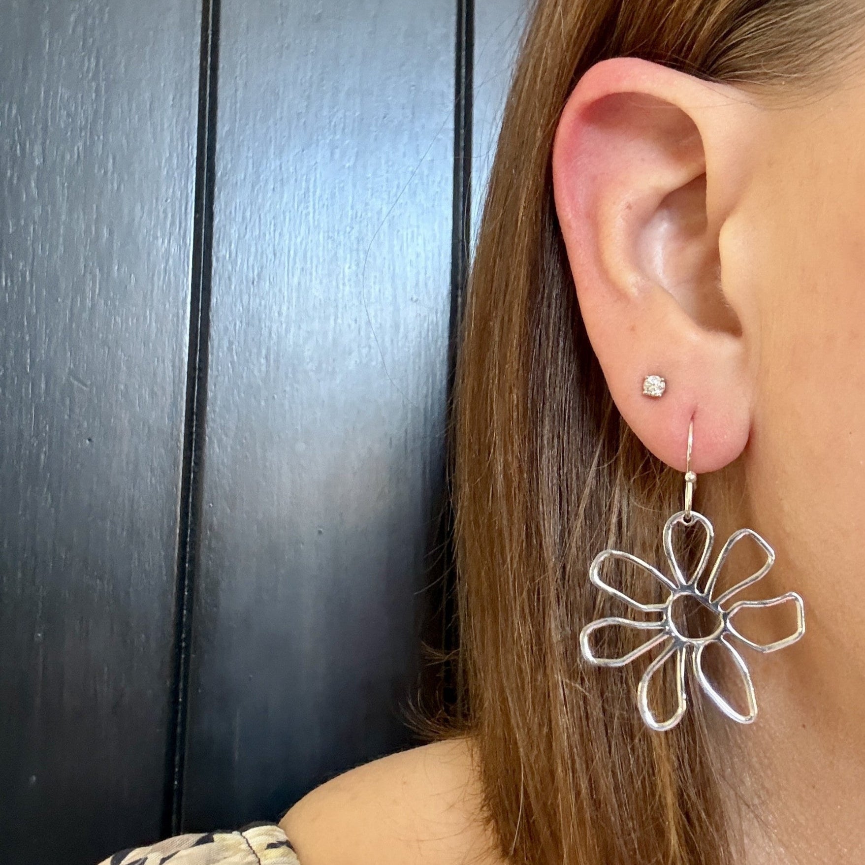 Model wearing Silver daisy floral earrings with lightweight open petal design by Half Turn Designs