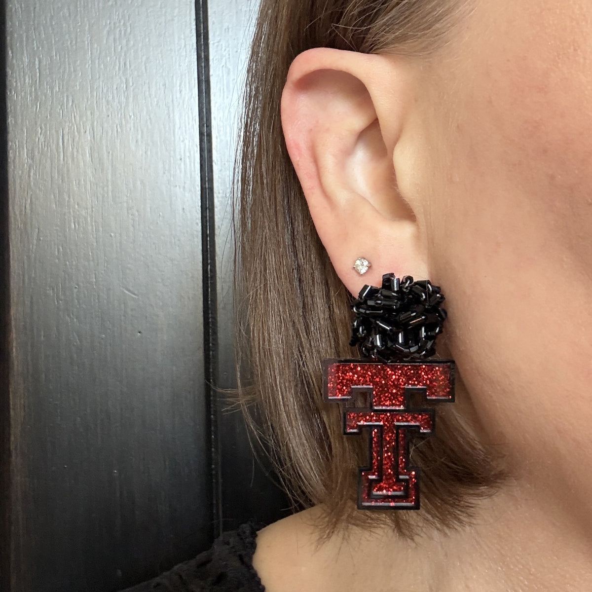 Model wearing Texas Tech Red Glitter Game Day Dangles with black bead studs.