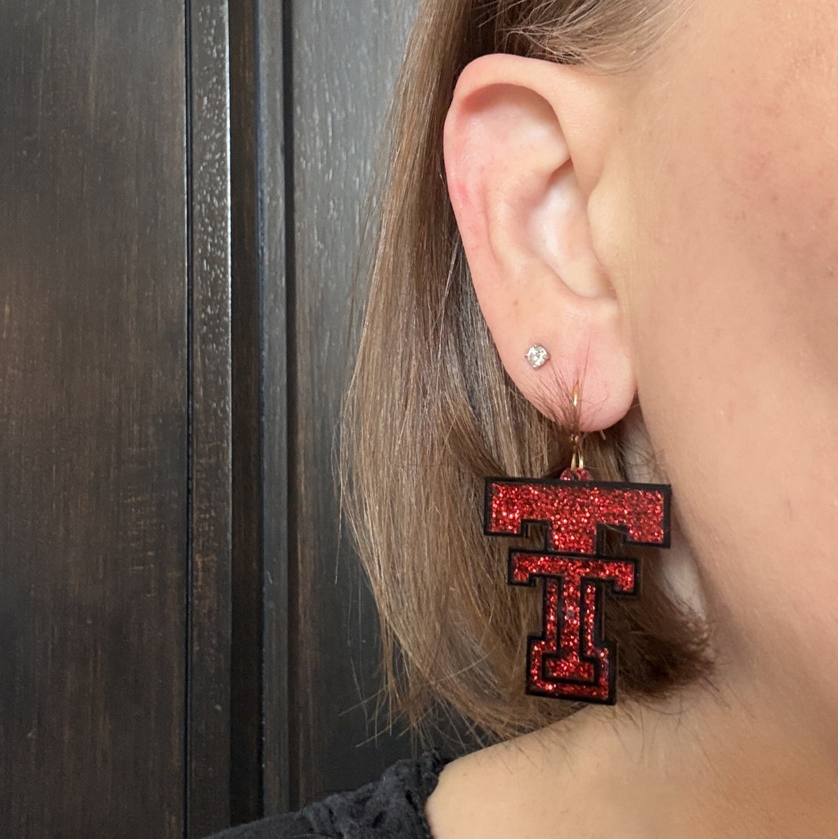 Model wearing Texas Tech Red Glitter Game Day Dangles with gold-tone Stainless Steel earring hooks.