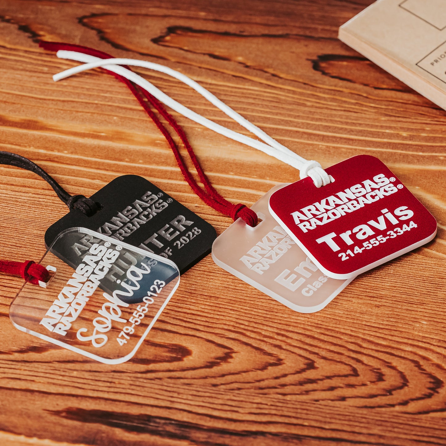 Officially licensed University of Arkansas Razorbacks acrylic luggage tags. These luggage tags are 2" squares, available in 1/8" or 1/4" clear, frosted, black or crimson acrylic, each engraved with a name and contact information by Half Turn Designs