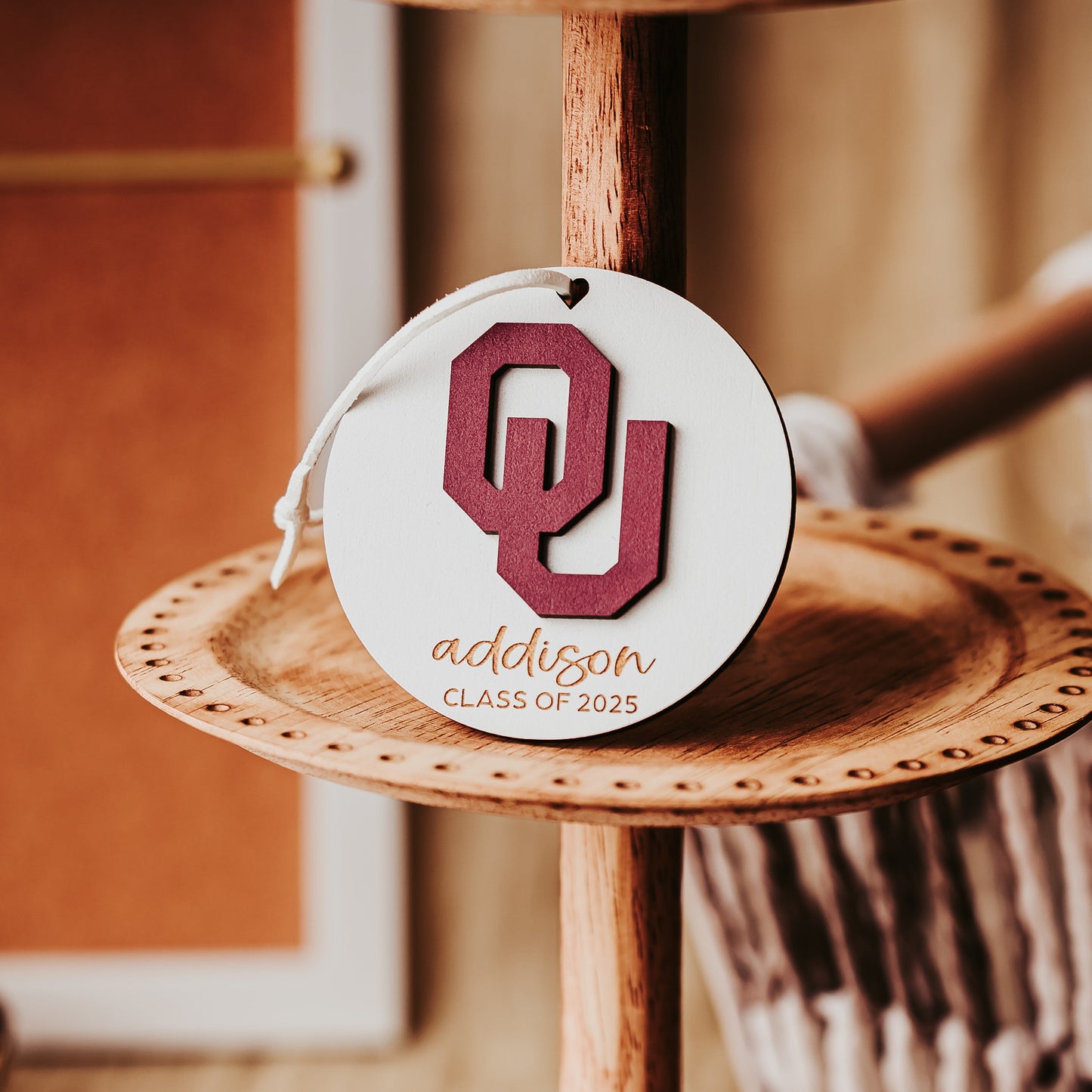 Engraved University of Oklahoma ornament featuring crimson OU logo on 3-inch round wood ornament, customizable with name or phrase, available in Cherry, Mahogany, Walnut, Sapele, or White finishes. Perfect Sooner Christmas gift or car charm. Shown here in White wood option.