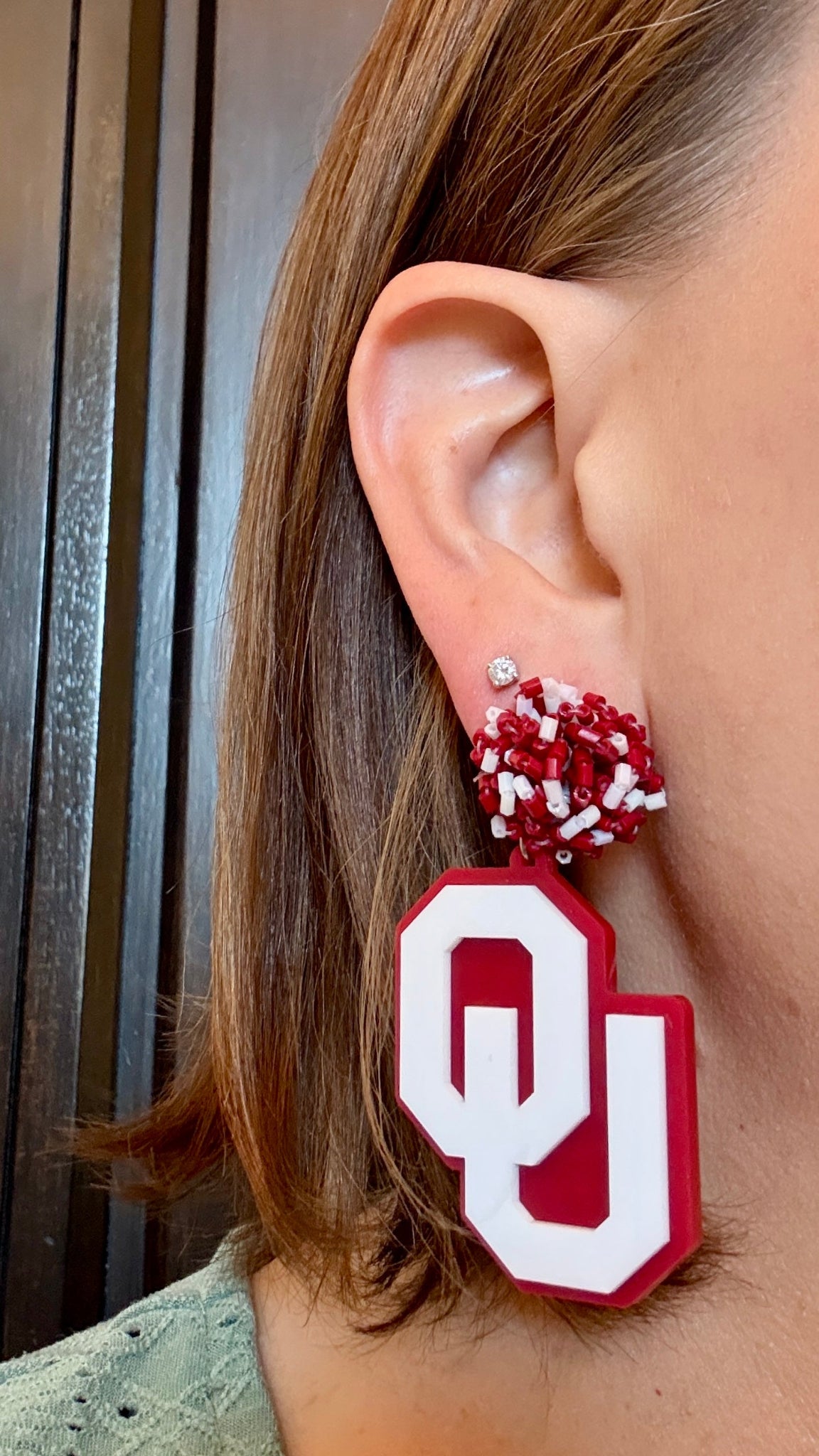 Model wearing white on crimson glitter with crimson and white beaded toppers. These earrings are officially licensed University of Oklahoma game day earring collection by Half Turn Designs. These earrings are available in combinations of crimson and white acrylic, including glitter. Available in a eight different fun toppers for OU game days and as a gift for your favorite Oklahoma Sooner.