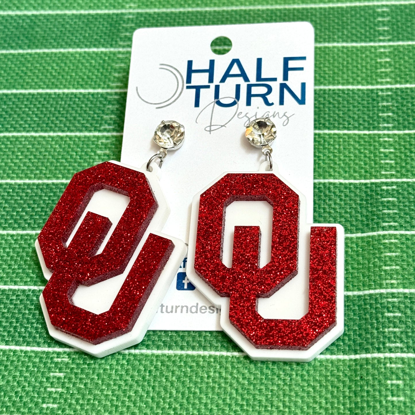Officially licensed University of Oklahoma game day earring collection by Half Turn Designs. These earrings are available in combinations of crimson and white acrylic, including glitter. Available in a eight different fun toppers for OU game days and as a gift for your favorite Oklahoma Sooner.  Crimson Glitter on White with Rhinestone topper on silver hardware shown here.