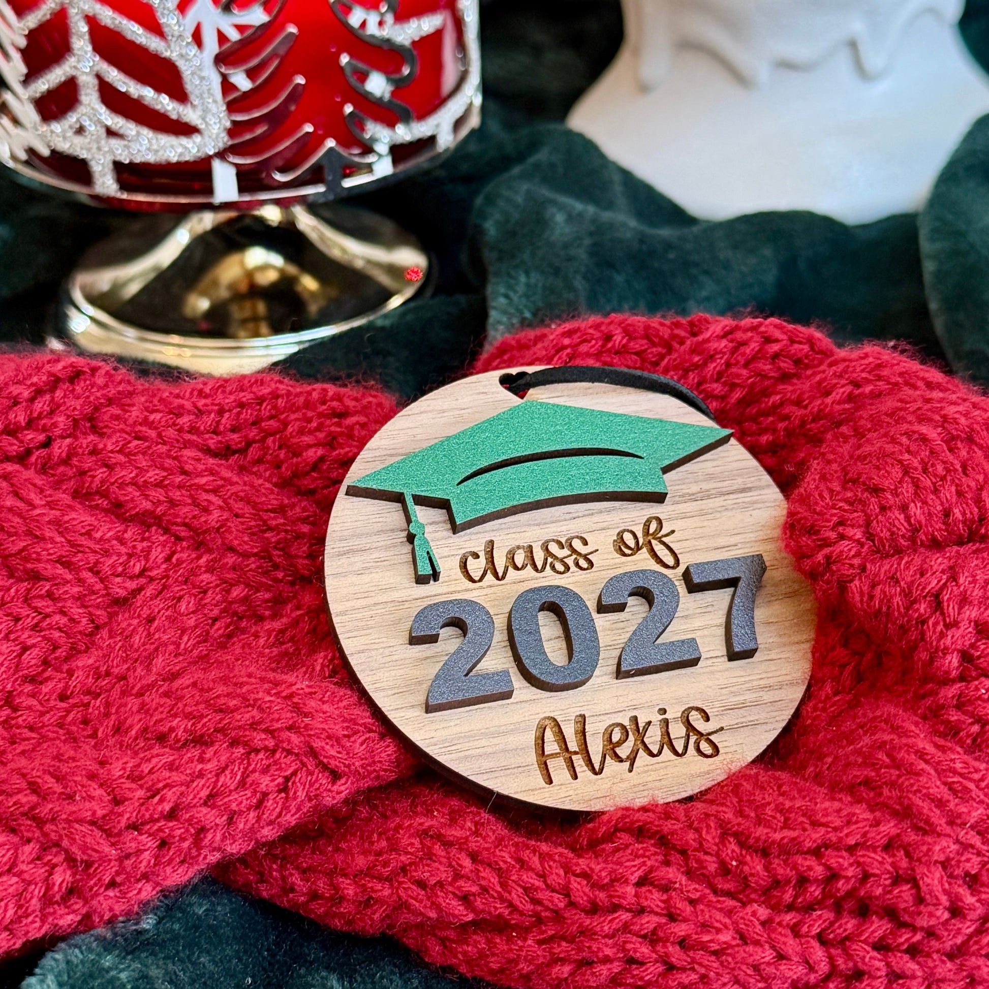 Personalized Class of 2027 wooden ornament in mahogany finish with green graduation cap, raised black 2027 numbers and graduate's engraved name