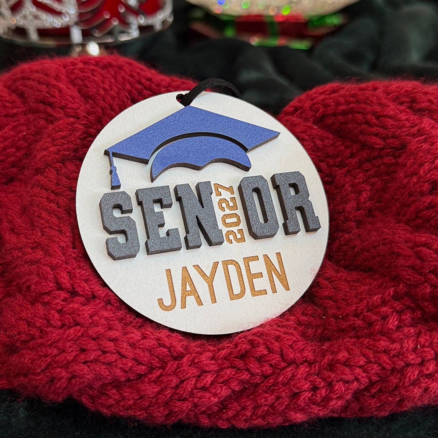 Personalized Senior 2027 wooden ornament in white with blue graduation cap, engraved with the graduate's name