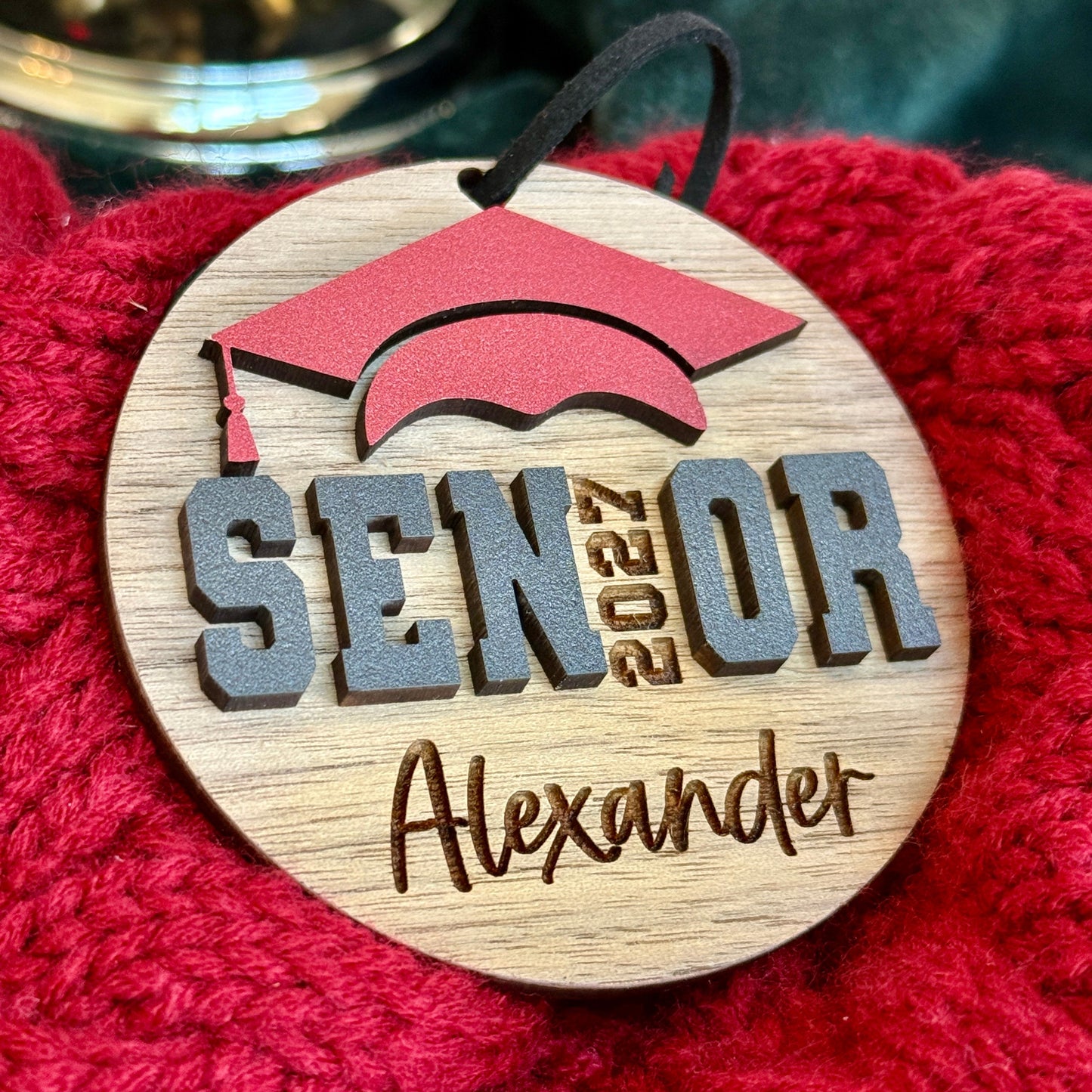 Personalized Senior 2027 Ornament in walnut wood finish with red graduation cap and engraved graduate's name