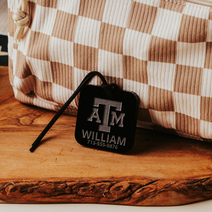 Officially licensed Texas A&M luggage tags in square shape, 2x2".  These acrylic luggage tags are personalized with 1-2 lines of text and come in 1/8" or 1/4" width.  Luggage tag colors include Clear, Frosted, Opaque Black, Shiny Black, Maroon that engraves white and Black that engraves white.  Opaque black acrylic version shown here.